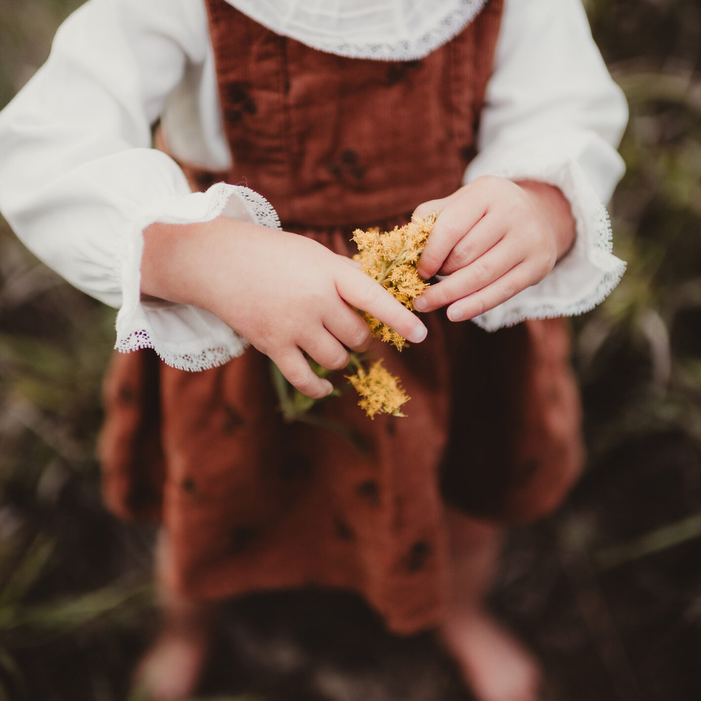 Little toddler girl holding yellow flowers in autumn dress