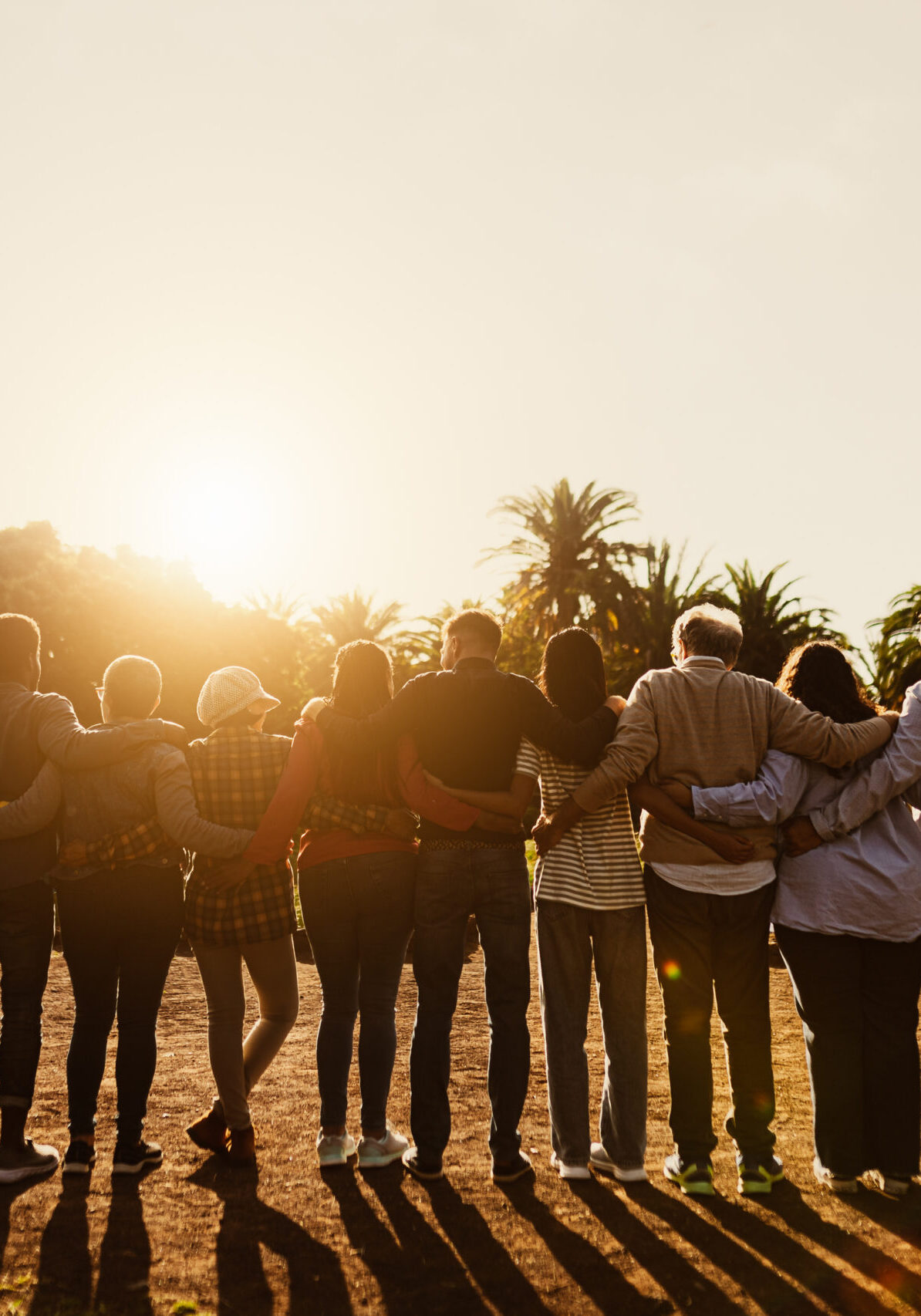 Back view of happy multigenerational people having fun in a public park during sunset time - Community and support concept